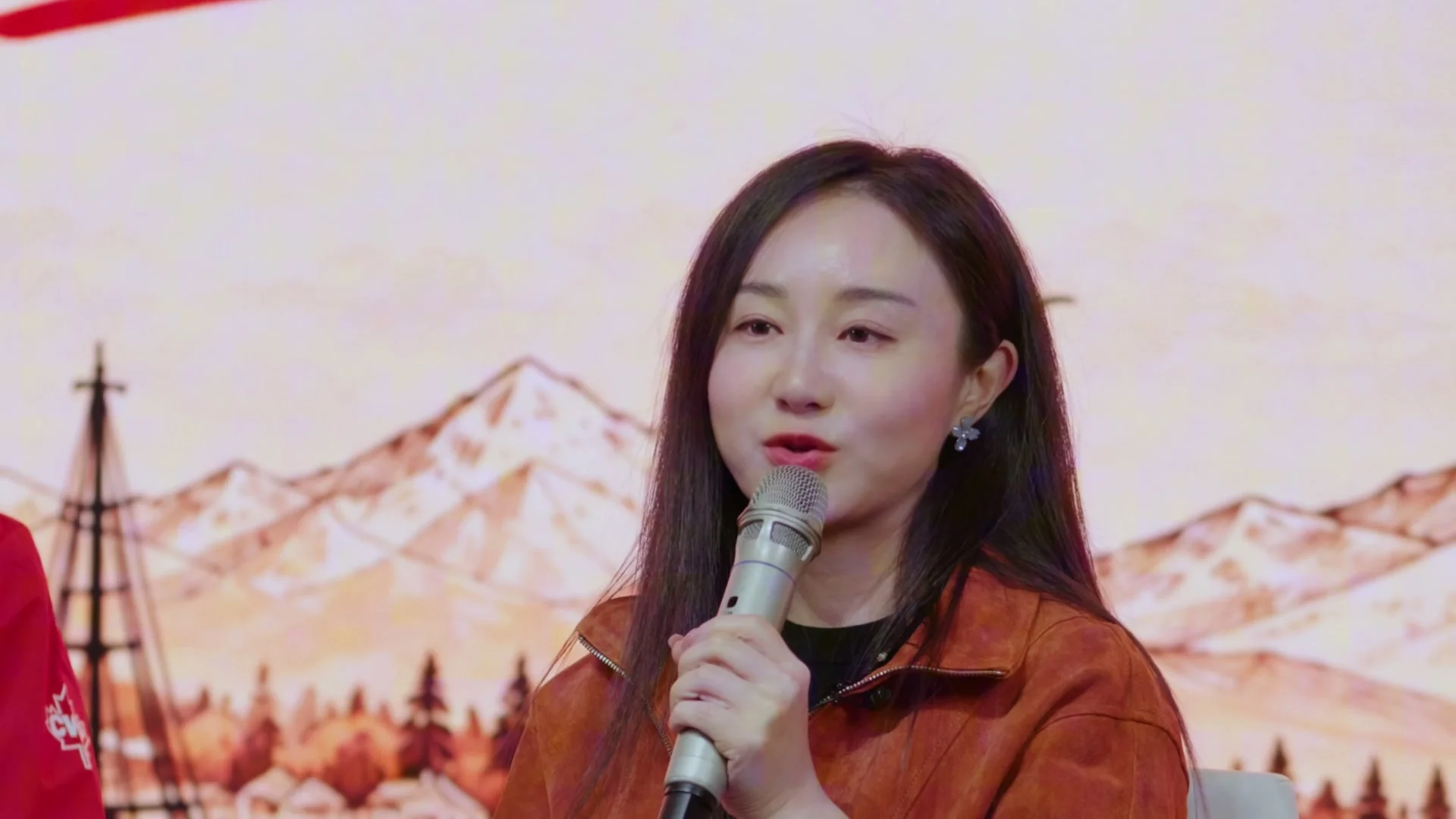 Host Sarah Yu holding a microphone during the CanWest dialogue at Upperland Studio