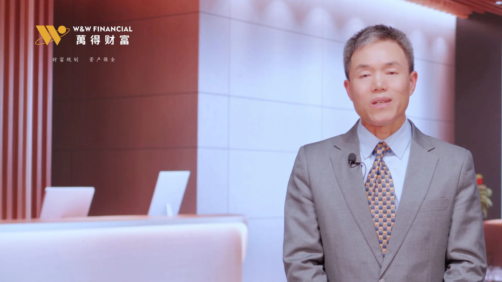 萬得財富创始人佩戴领夹麦克风，在室内出镜讲述公司理念
