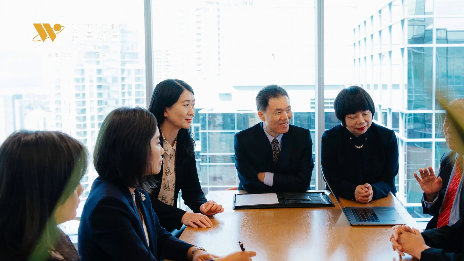 萬得財富团队围坐会议桌交流，企业宣传片中的会议场景